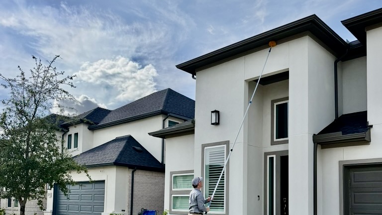 EnviRx Pest Professional removing spider webs and wasp nests from the roofline with an extender pole and web head 